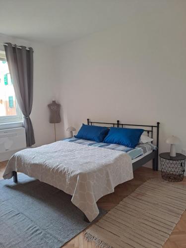 a bedroom with a large bed with blue pillows at Serenissima Retro Apartment in Muggia