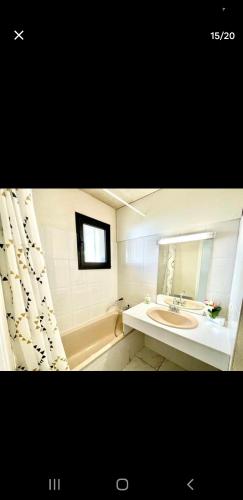 une salle de bain avec un lavabo, une baignoire et un miroir dans l'établissement Appartement avec terrasse et jardin, à Royan