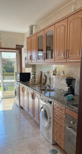 a kitchen with a sink and washing machines in it at Flamant apart in Aguçadoura
