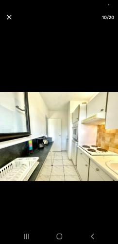 Il comprend une cuisine avec des placards blancs et du carrelage blanc. dans l'établissement Appartement avec terrasse et jardin, à Royan