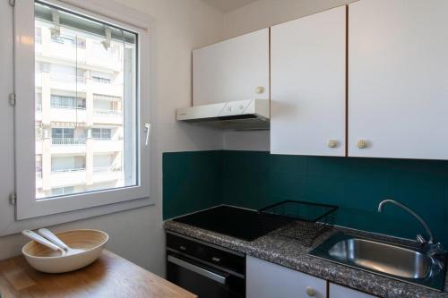 une cuisine avec des armoires blanches, un évier et une fenêtre dans l'établissement #46 Terrace AC 4mins walk Sea Tram T2 Airport Port, à Nice