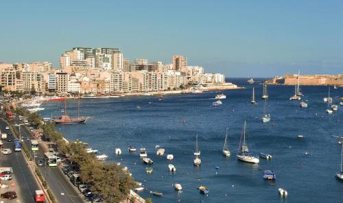 a group of boats in the water next to a city at The Howard Hotel in Sliema
