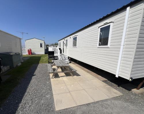 a row of benches next to a white trailer at 3 Bedroom Modern Caravan Sleeps up to 8 in Millom