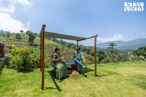 two people sitting on a bench under a canopy at StayVista at Ambrosia access to water stream in Kotagiri
