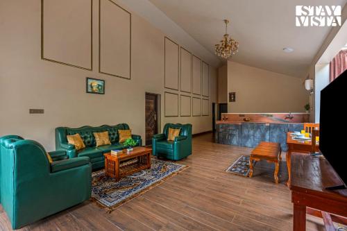 a living room with two green couches and a table at StayVista at Ambrosia access to water stream in Kotagiri
