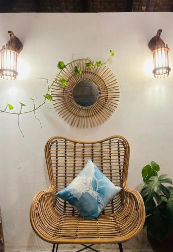 a wicker chair with a blue pillow and a mirror at Thundi Sea View in Fulidhoo