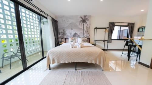 a bedroom with a bed and large windows at Mitsu Guesthouse in Karon Beach