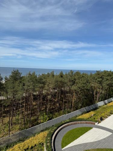 a winding road with a fence and the ocean at Waveview Premium Apartment Międzyzdroje in Międzyzdroje