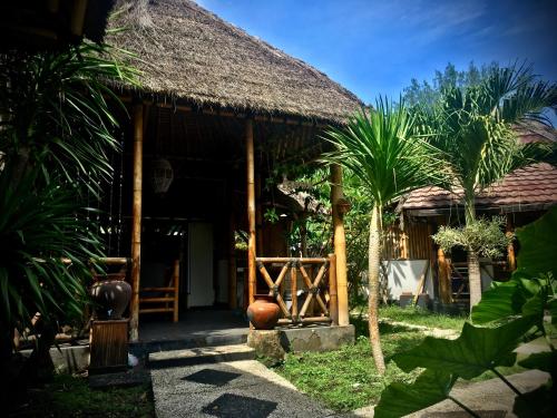 a small hut with a straw roof and palm trees at AlBambu in Gili Air