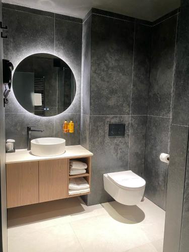 a bathroom with a sink and a toilet and a mirror at Grand Hotel Coroana in Bistriţa