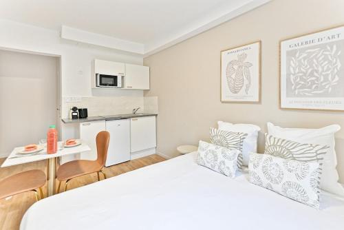 une chambre avec un grand lit blanc et une cuisine dans l'établissement Studio paisible et calme proche Paris- V, à Asnières-sur-Seine
