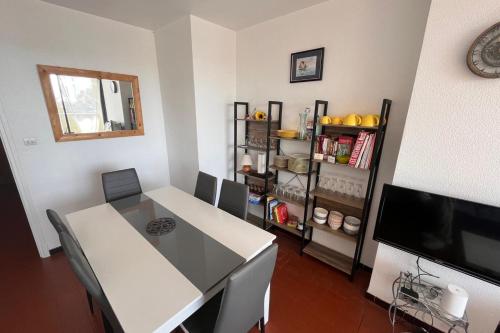 une salle à manger avec une table blanche et une télévision dans l'établissement Comfortable apartment of 60 m in Narbonne, à Narbonne