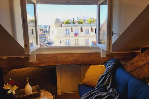 - un salon avec une grande fenêtre et un canapé bleu dans l'établissement Grimaldi - Sous les toits de Nice, à Nice