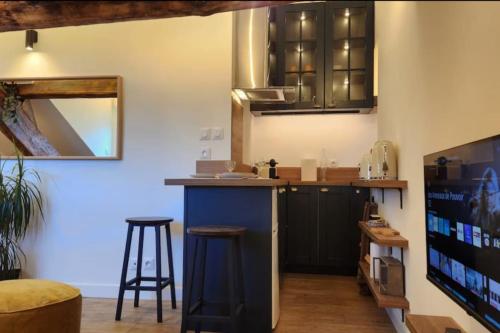 une cuisine avec des placards noirs et un bar avec des tabourets dans l'établissement Grimaldi - Sous les toits de Nice, à Nice