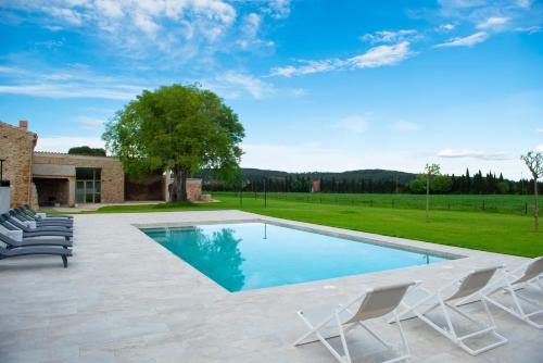 a swimming pool with chairs and a house at Casa Rural Mas Homs in Parets de Dalt