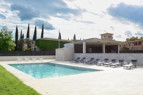 a swimming pool with chairs and a house at Casa Rural Mas Homs in Parets de Dalt