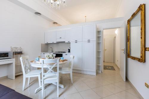 a white kitchen with a table and chairs and a mirror at Appartamento Achates in Acate