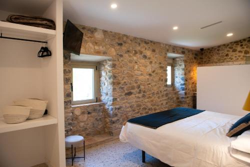 a bedroom with a bed and a stone wall at Casa Rural Mas Homs in Parets de Dalt
