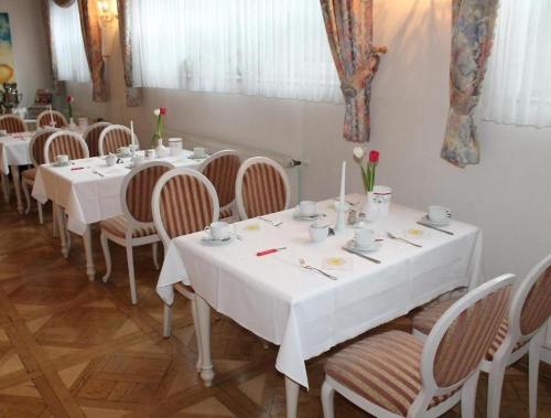 a dining room with white tables and chairs with roses on them at REGIOHOTEL Bunte Stadt in Wernigerode