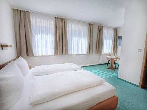 two beds in a hotel room with windows at REGIOHOTEL Bunte Stadt in Wernigerode