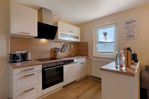 a kitchen with white cabinets and a stove top oven at Schwarzwaldliebe in Oberharmersbach
