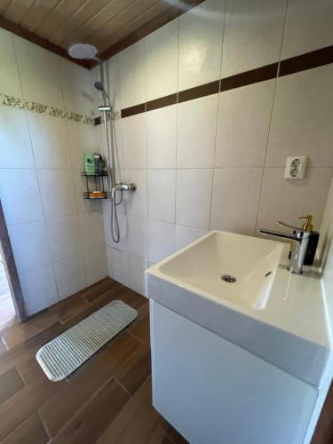 a bathroom with a white sink and a shower at Gintaro pirtelė in Lazdijai