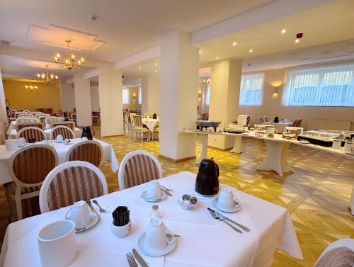 a dining room with white tables and white chairs at REGIOHOTEL Bunte Stadt in Wernigerode