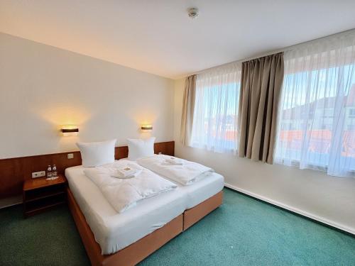 a bedroom with a large bed with a large window at REGIOHOTEL Bunte Stadt in Wernigerode