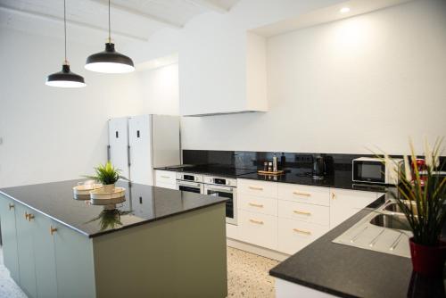 a kitchen with white cabinets and black counter tops at Casa Rural Mas Homs in Parets de Dalt
