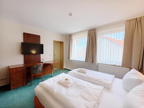 a hotel room with two beds and a desk at REGIOHOTEL Bunte Stadt in Wernigerode