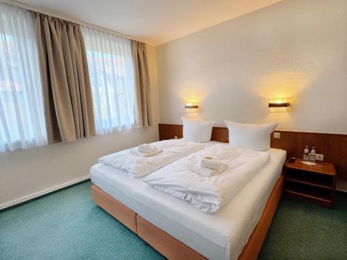 a hotel room with a large bed with white sheets at REGIOHOTEL Bunte Stadt in Wernigerode