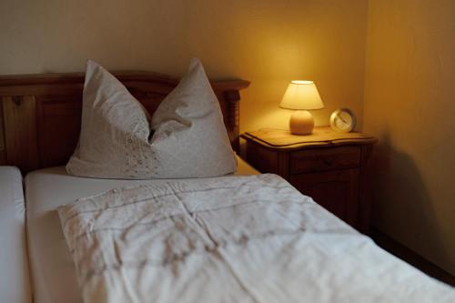 a bed with white sheets and pillows with a lamp at Schwarzwaldliebe in Oberharmersbach