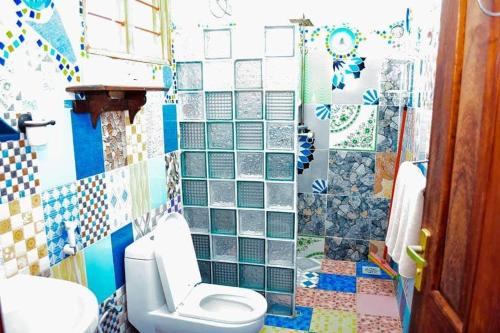 a bathroom with a toilet and a tiled wall at COCCOBELLO AFRICAN Village- in Nungwi