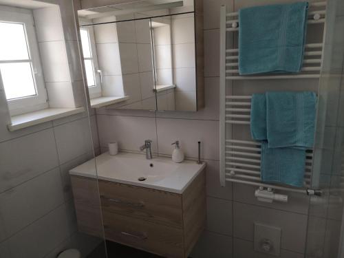 y baño con lavabo, espejo y toallas azules. en Ferienwohnung Beim Schuster, en Hitzleried