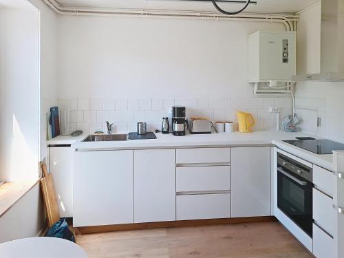 une cuisine blanche avec des armoires et des appareils blancs dans l'établissement Petite maison de pêcheur dans un site paradisiaque, à Ploulech