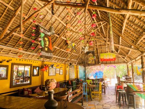 a restaurant with wooden ceilings and tables and chairs at COCCOBELLO AFRICAN Village- in Nungwi