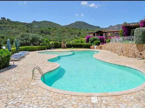 a swimming pool with a stone walkway around it at Appartamento pittulongu in Olbia