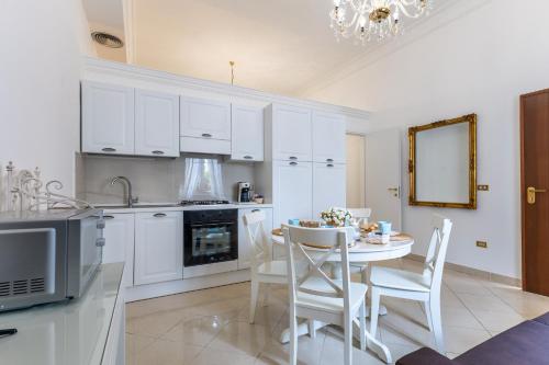 a kitchen with white cabinets and a table and chairs at Appartamento Achates in Acate
