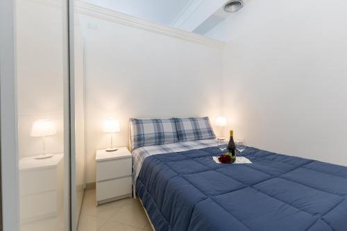 a bedroom with a blue bed with a bottle of wine at Appartamento Achates in Acate