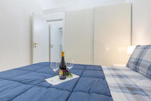 a bottle of wine and two glasses on a bed at Appartamento Achates in Acate