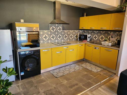 a kitchen with yellow cabinets and a washing machine at L'@ppart in Châtillon-sur-Chalaronne