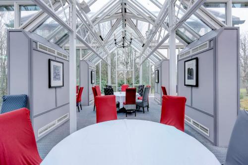 a dining room with a white table and red chairs at The Landmark Hotel and SPA Leisure Club Dundee By Sunday in Dundee