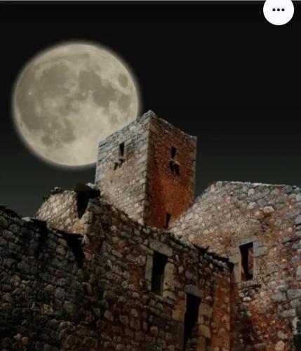 a full moon rising over an old building at Filia's House (The House of Friendship) in Areopolis
