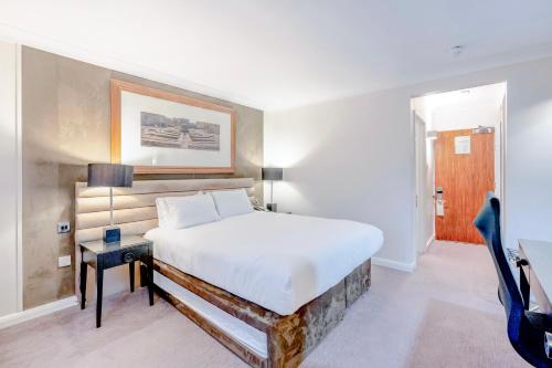 a bedroom with a large bed and a table at The Landmark Hotel and SPA Leisure Club Dundee By Sunday in Dundee