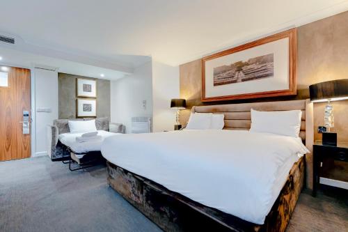 a hotel room with a large bed and a chair at The Landmark Hotel and SPA Leisure Club Dundee By Sunday in Dundee