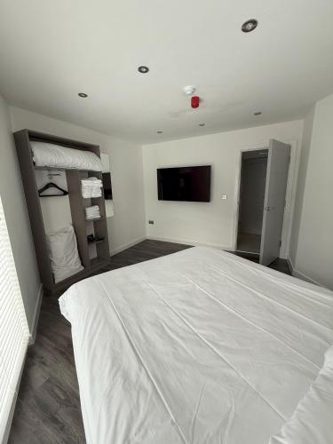a bedroom with a large white bed and a flat screen tv at Coastal Plaza in Blackpool