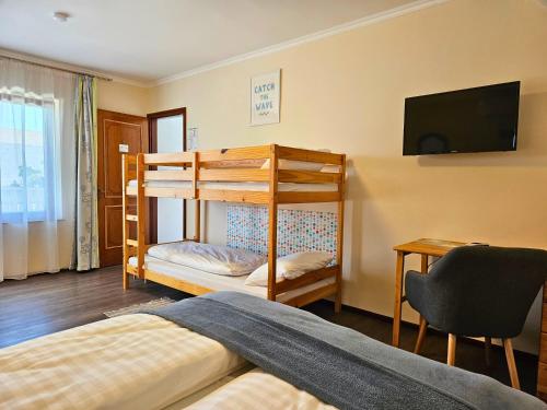 a bedroom with bunk beds and a desk and a television at Felhő Vendégház in Keszthely