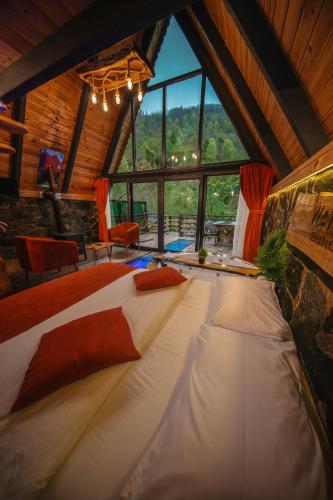 a large bed in a room with a large window at Waterfall suit bungalov in Çamlıhemşin