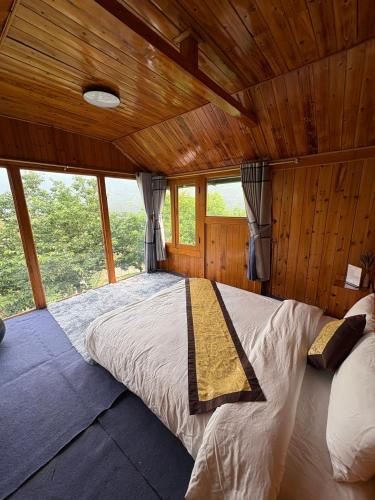 a large bed in a wooden room with windows at Sapa Eco Hugo in Sa Pa