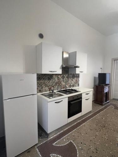 a white kitchen with a stove and a refrigerator at da ivan in Porto Cesareo